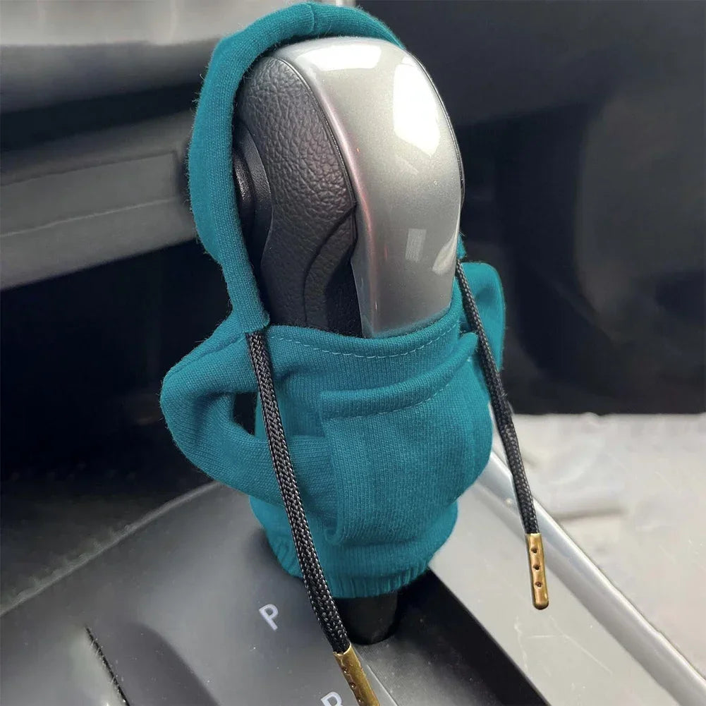 Car gear shift with a teal sweater wrapped around it, inside a vehicle.