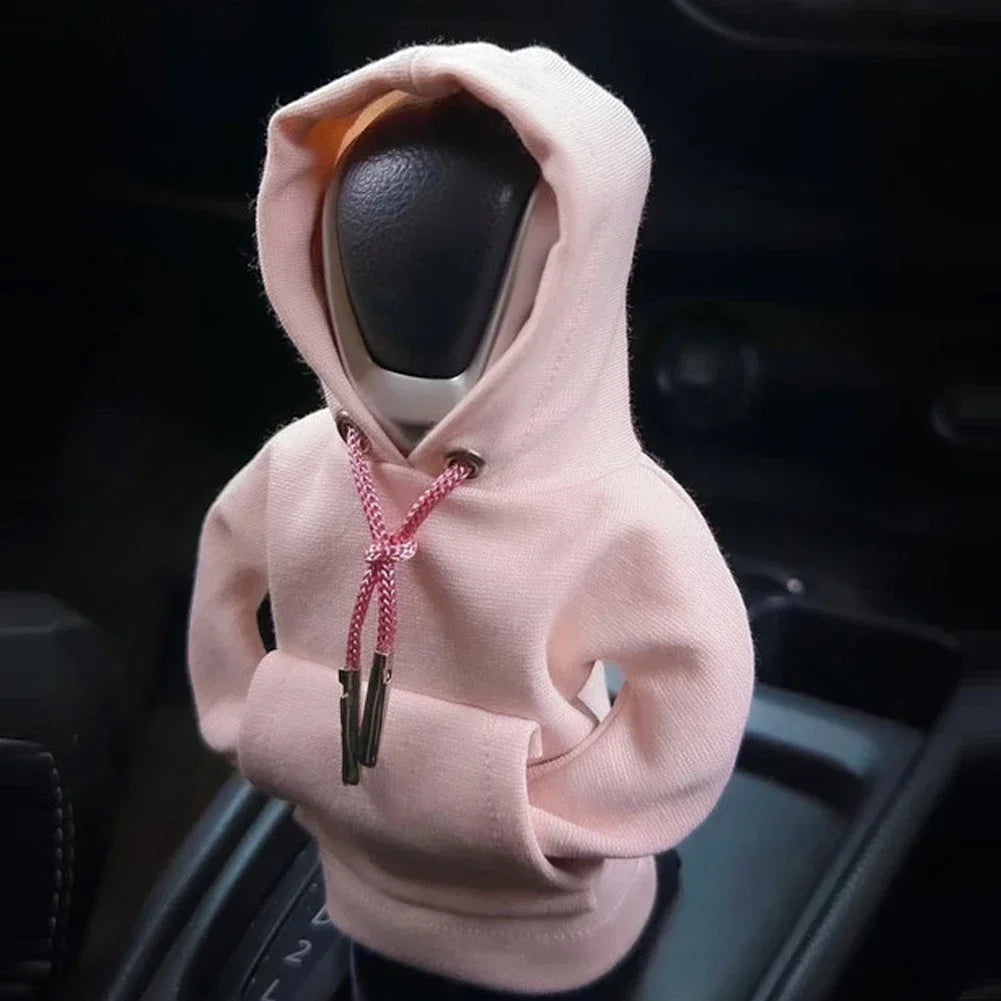 Car steering wheel cover with a pink hoodie over it, inside a car.
