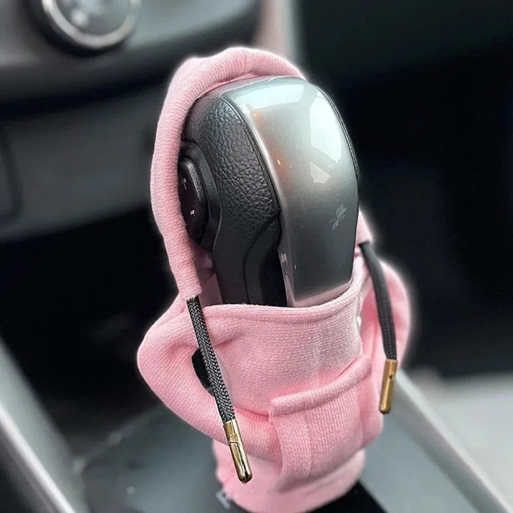 Pink car gear shift cover with gold accents on a car's transmission shifter.