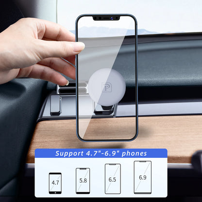 Hand holding a smartphone with a screen protector, placed on a car dashboard.