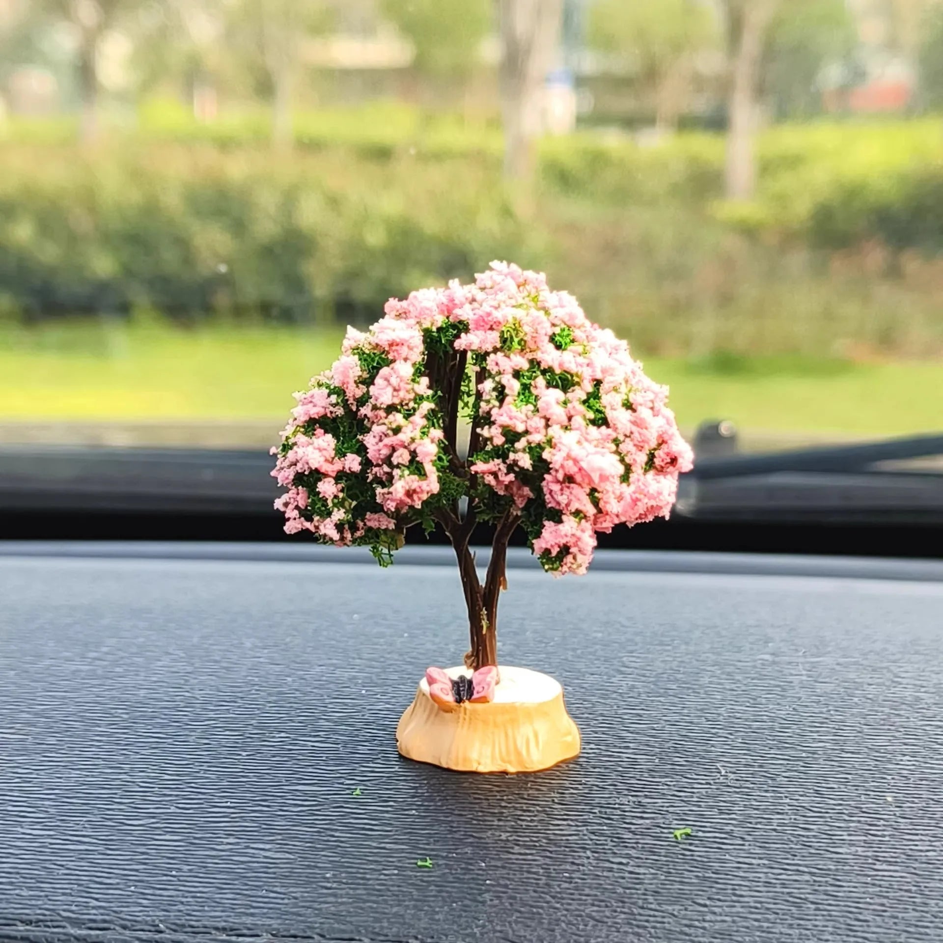 Small decorative tree with pink flowers on a vehicle dashboard