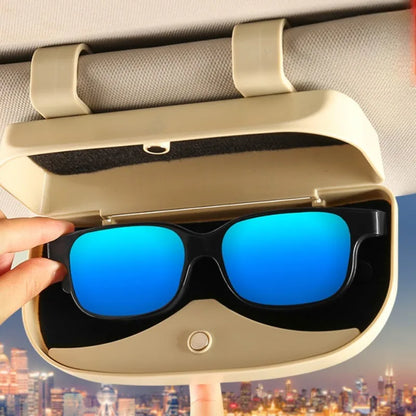 Sunglasses being placed into a car visor holder with a cityscape in the background