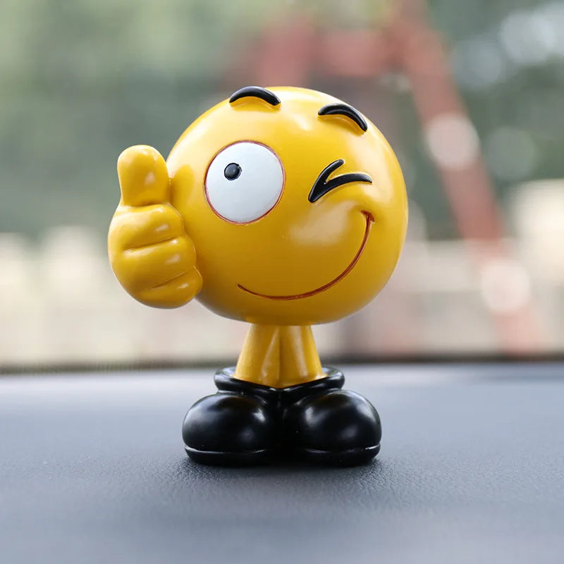 Yellow emoji figurine giving a thumbs up on a car dashboard